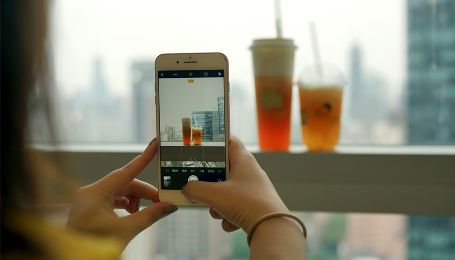 person taking a picture of two drinks on a ledge of a window