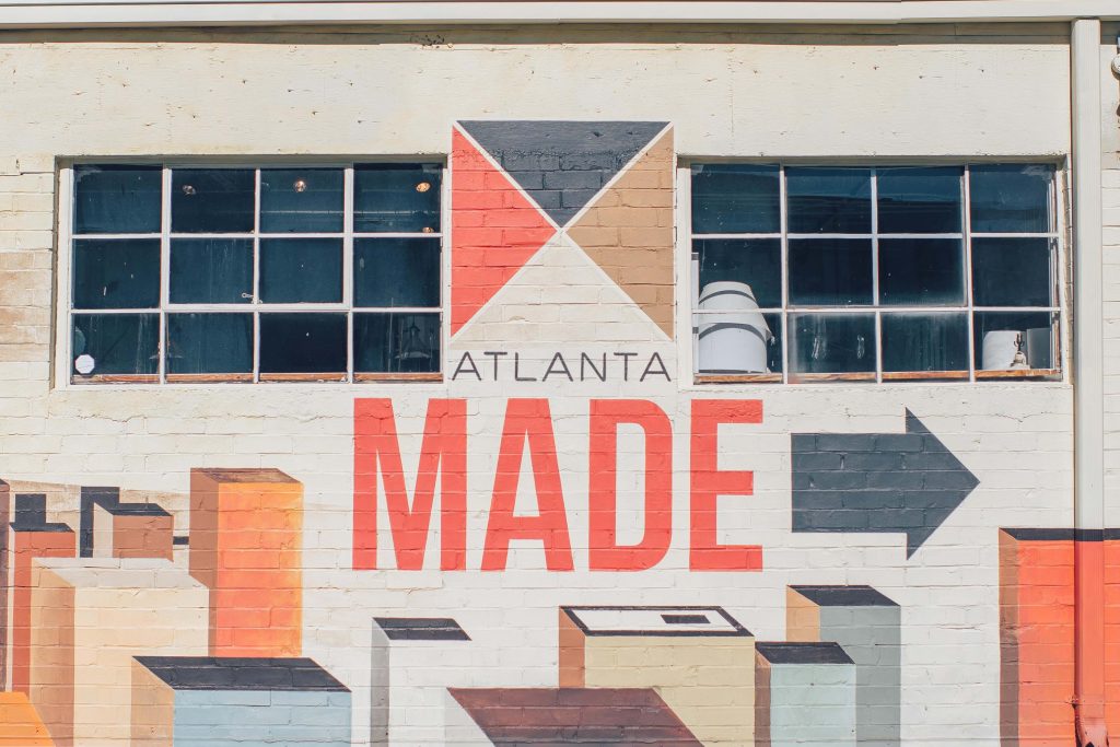 brick wall painted with sign that reads Atlanta Made with an arrow pointing right