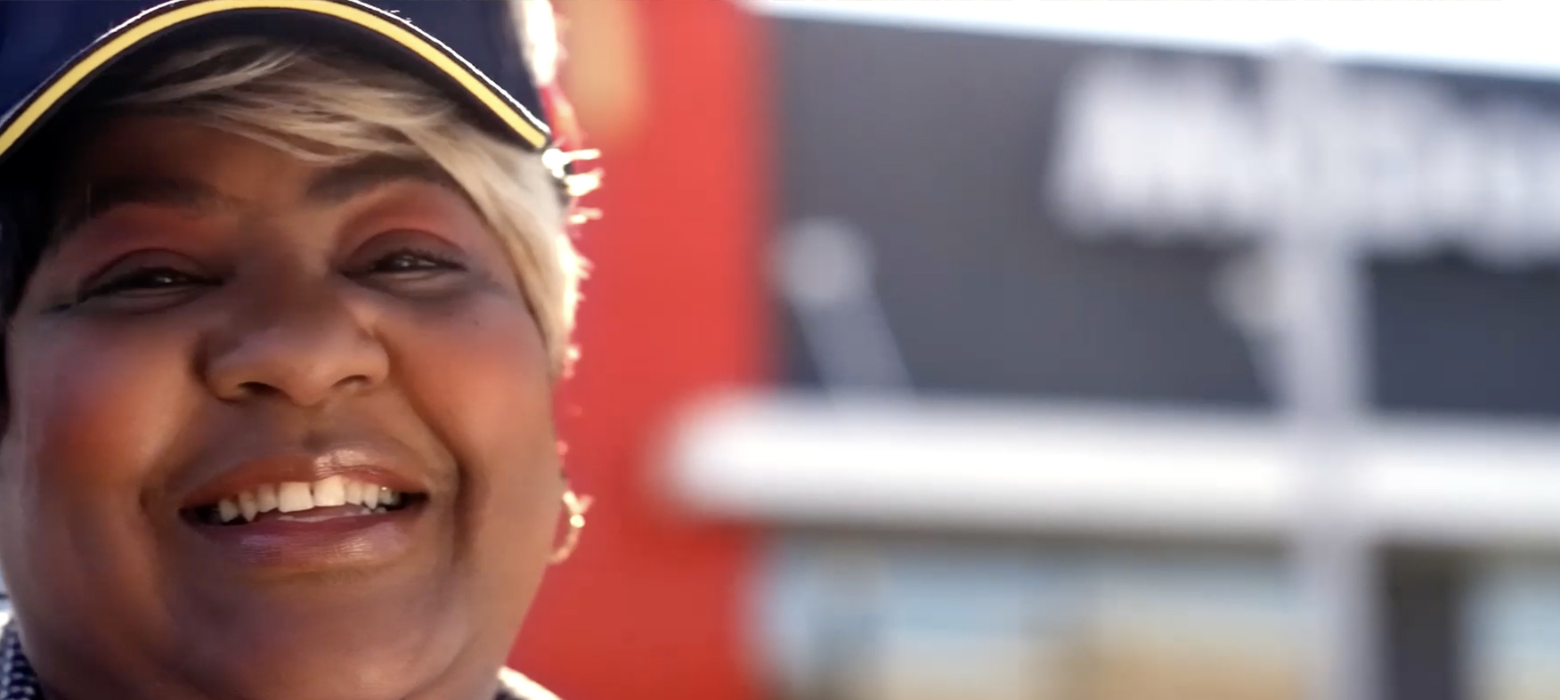 female McD worker smiling in front of McDonald's store