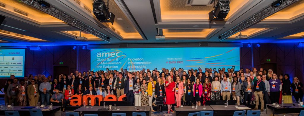 A large group of professionals gathered for a group photo at the AMEC Global Summit on Measurement and Evaluation.