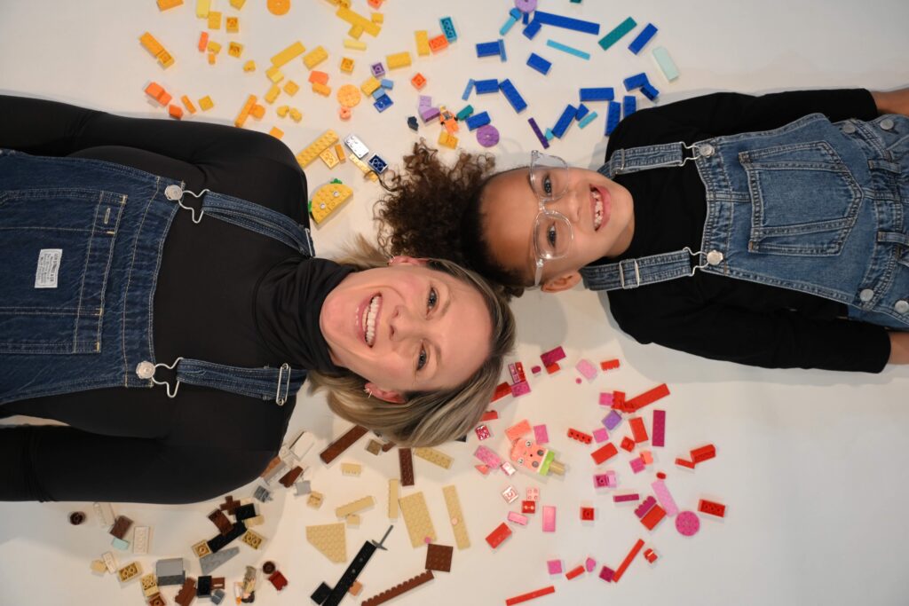Jody Benjamin and her daughter posed against multicolored LEGOs.